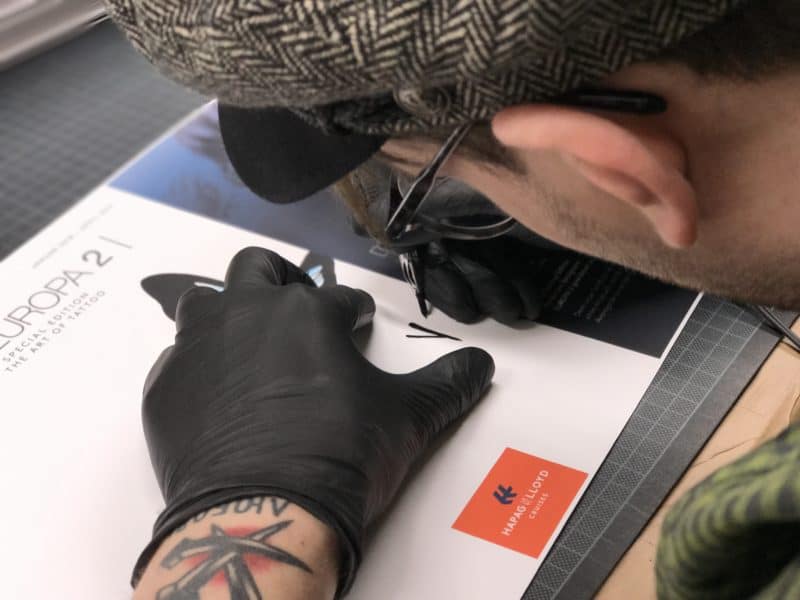 Tobi Tietchen signiert 100 MS Europa 2 Kataloge mit der Tattoo-Nadel